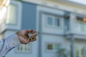 husägare innehav en ny hus nyckel från en mäklare efter håller med till köpa en bolånehem investering. begrepp uppköp en hus , en ny Hem. foto