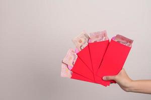 kvinna innehav kinesisk röd kuvert med thai baht pengar gåva för Lycklig lunar ny år Semester foto