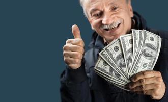Lycklig äldre man som visar fläkt av pengar foto