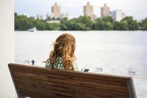 2022-07-17. Ryssland. Moskva. nordlig flod station. en flicka med lång hår är Sammanträde på en bänk, beundrande de se av de flod. se från de tillbaka. Övrig människor är vilar närliggande. foto