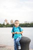 en pojke i en blå t-shirt med en ryggsäck på hans tillbaka. resa. de ansikte uttrycker naturlig glad känslor. inte iscensatt foton från natur