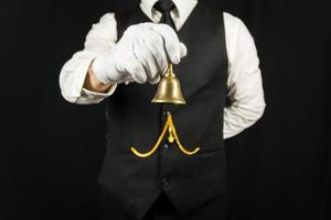 porträtt av butler eller servitör i vit handskar innehav mässing klocka. begrepp av service industri och professionell gästfrihet och artighet. foto