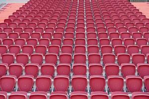 rosa plast stolar på de läktare tittar på fotboll tändstickor på stor stadion. foto