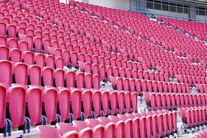 rosa plast stolar på de läktare tittar på fotboll tändstickor på stor stadion. foto