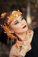 närbild ansikte av ett asiatisk kvinna i smink bär guld krona och guld Tillbehör med skön ansikten foto