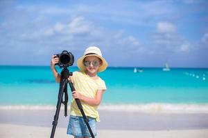 flicka med kamera på ett stativ på en strand foto