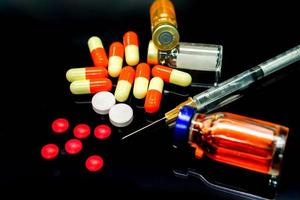plast spruta, kapsel mediciner, injektion läkemedel i flaskor, vit och röd piller mediciner isolera på svart bakgrund. anta till amfetamin eller narkotisk missbruk. foto