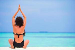 kvinna som utövar yoga på stranden foto