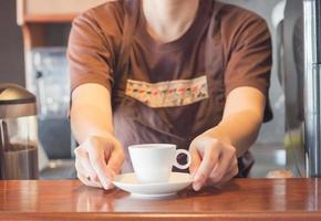 barista som erbjuder en vit kopp kaffe foto