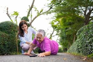 asiatisk senior kvinna föll ner på liggande golv eftersom svag och lem svaghet och gråt i smärta form olycka och henne dotter kom till hjälp Stöd. begrepp av gammal äldre försäkring och hälsa vård foto