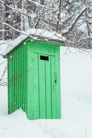 rustik utomhus- trä- toalett i en snöig skog foto