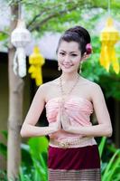 skön thai flicka i thai traditionell kostym och thailändska hälsning gest foto