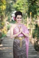 skön thai flicka i thai traditionell kostym i thailändska hälsning gest foto