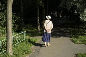 pensionär promenader i parkera i sommar. kvinna promenader på väg. promenad på sommar dag. foto