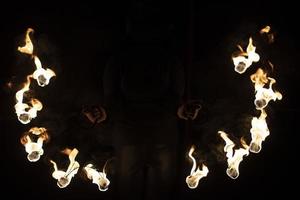 eldshow i mörk. två stål fläktar med varm lågor. foto