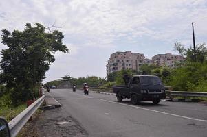 surabaya, Indonesien, 2022 - se av en upptagen motorväg med träd förbi de sida av de väg under de dag foto