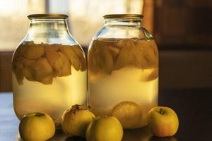 äpple kompott i glas burkar på de kök tabell, mjuk kväll ljus foto