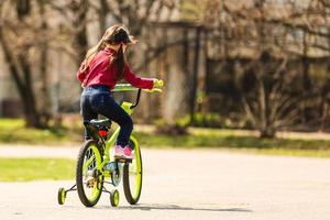 barn ridning på en cyklar på asfalt väg i de parkera i sommar foto