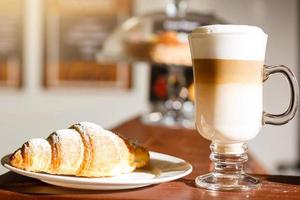 kaffe latte och croissant på en trä- tabell foto