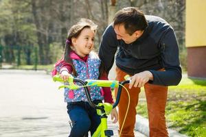 far undervisning dotter till rida cykel i trädgård foto