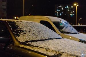 bil med de frysta glasögon täckt med is och snö i en vinter- frostig natt foto
