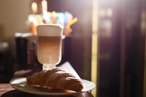 kaffe latte och croissant på en trä- tabell foto