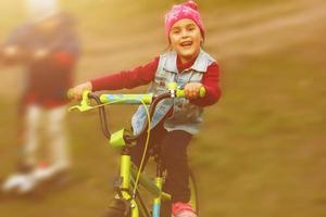 liten flicka med hjälm ridning cykel på solnedgång foto