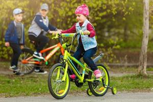 leende liten flicka på en cykel. foto