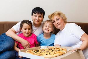 familj middag. mor och barn äter en stor pizza foto