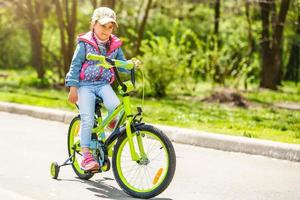 barn på en cykel på asfalt väg i sommar. cykel i de parkera foto