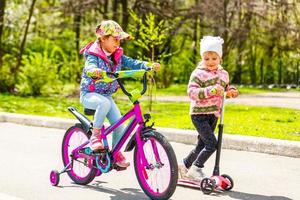 flickor ridning ner de gata på skotrar och en cykel foto