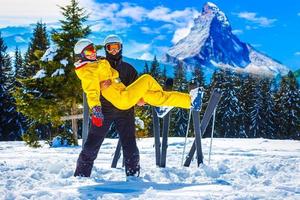 Lycklig man och kvinna skidåkare mot de bakgrund av snöig bergen foto