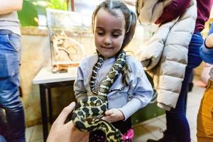 liten flicka med en orm. ormar i en terrarium. foto