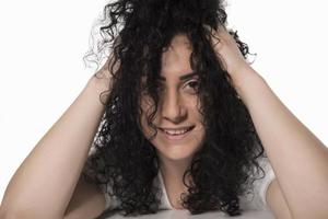ung kvinna påfrestande till hårkam henne lockigt hår foto
