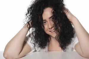 ung kvinna påfrestande till hårkam henne lockigt hår foto