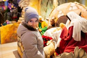 jul nativity spjälsäng scen i kyrka. bebis flicka mot stabil med bebis Jesus i en krubba, mary och joseph. foto