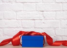 blå kartong låda med gåva och röd silke band foto