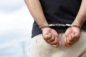 fånge manlig kriminell stående i handklovar med händer Bakom tillbaka. foto