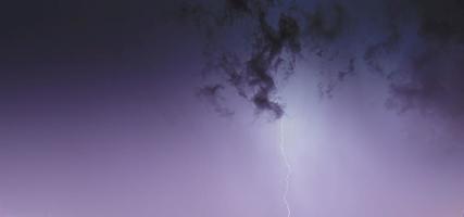 bild av en blixt i de natt himmel med lysande moln foto