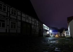 natt scen av ett gammal tysk stad med dubbverk hus och kullerstensbelagda gata i våt väder foto
