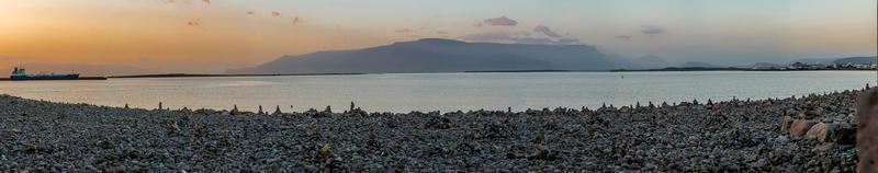 panorama- bild av reykjavik hamn med stenig strand på solnedgång i sommar foto