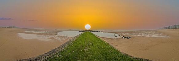 panorama- bild längs en vågbrytare på de norr hav strand middlekerke foto