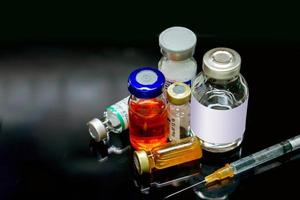 vacciner och injektioner läkemedel i injektionsflaska olika storlekar med en plast spruta på svart bakgrund. foto