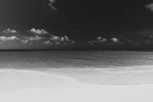 lugn svart och vit strand scen. dramatisk ö Strand landskap, mörk himmel med lugna vatten. svartvit tropisk kust, mjuk sand, naturlig utomhus- havet. lyx abstrakt sommar resa semester foto