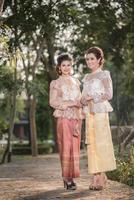 två skön flickor få klädd i thai traditionell kostym foto