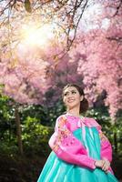 hanbok, de traditionell koreanska klänning och skön asiatisk flicka med sakura foto