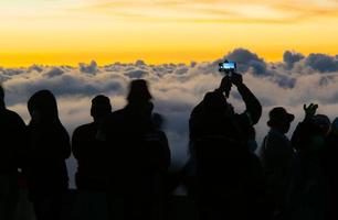 silhuett person grupp tittar på flytande hav av moln, hav av dimma, himmel ovan moln, tar clouds foton med mobil telefoner i de morgonsol stiga, resa lång helg, inhanon berg.