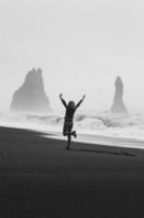 upphetsad turist på tömma svart strand svartvit naturskön fotografi foto