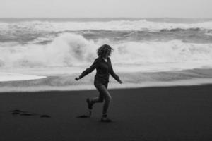 turist löpning längs reynisfjara strand svartvit naturskön fotografi foto