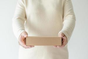 kvinna händer bärande brun kartong låda. begrepp av använder sig av återvinna papper låda. foto